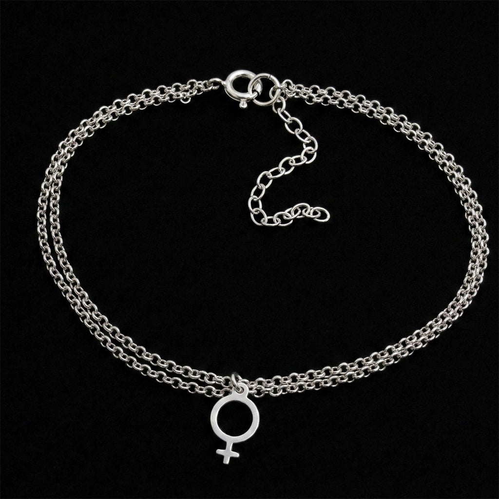 Dubbelradig fotlänk i 925 sterling silver med ett hänge format som en kvinnosymbol, fotograferad mot en svart bakgrund.